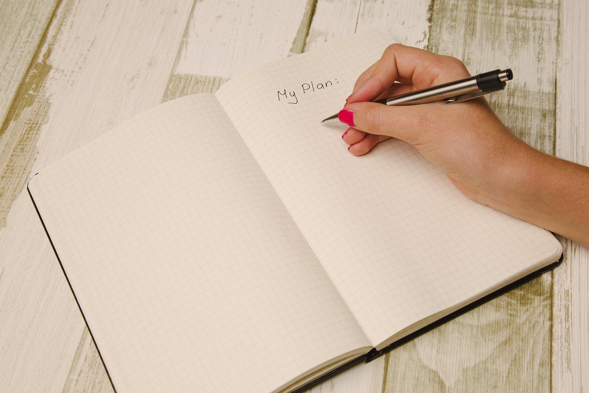 ノートにペンで書き込んでいる手元